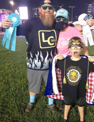 Local Philip Breeden, posing with wife Carmen, holds up his ribbons after placing 12th overall and third in ribs competition at the 41st World Series of BBQ in Kansas City, Kansas, the weekend of September 16-19. Also pictured is their eight-year-old son,