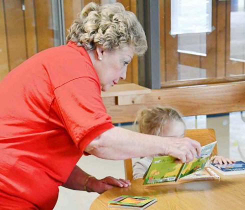 Bandera County Retired Teacher Sherrie Keese helps a youngster at Medina Elementary School select a book to take home for Christmas. BULLETIN PHOTO/Tracy Thayer