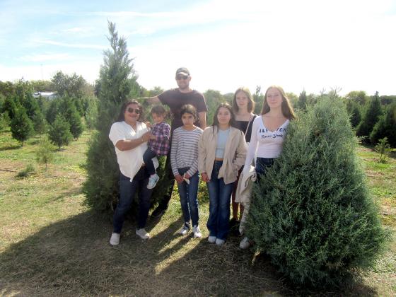 The Frisbee family, who recently moved to the area from Virginia, poses with the two Christmas trees they bought last week on the opening day of the Pipe Creek Christmas Tree Farm.