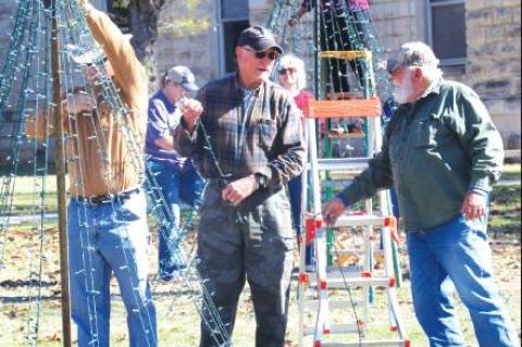 BULLETIN PHOTO/Bill Pack                      Mike Lloyd, left, Marcus Kaspar, center, and Grady Desmuke adjust lights on one of the Christmas trees on the Bandera County Courthouse grounds on Saturday, Nov.                                23, wh